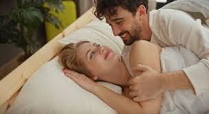 Homme et femme heureux au lit, illustrant comment tenir plus longtemps au lit naturellement